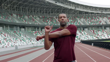 Portrait-of-African-American-Black-male-warming-up-before-running-on-an-empty-stadium-track-early-in-the-morning.-Shot-with-anamorphic-lens